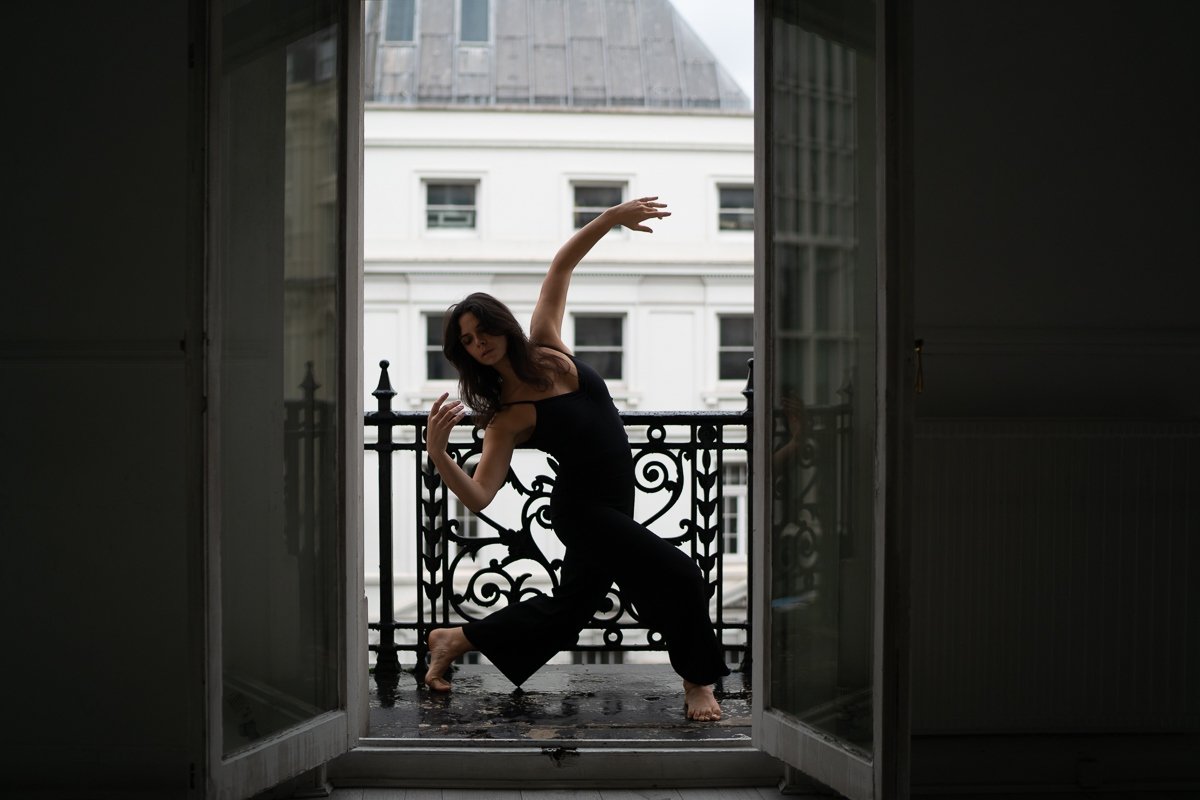 Sarah Hirsch performing a lunge with arm raised on a sunlit balcony