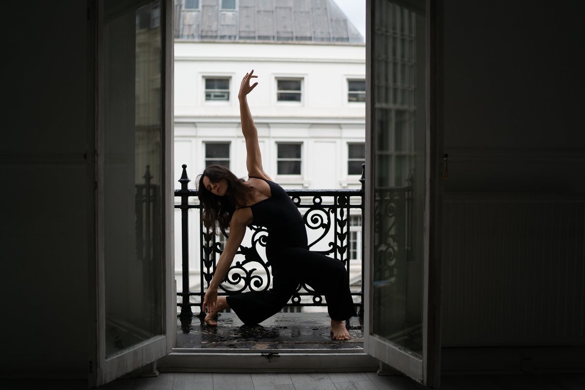 Sarah performing a lunge on a balcony with French doors