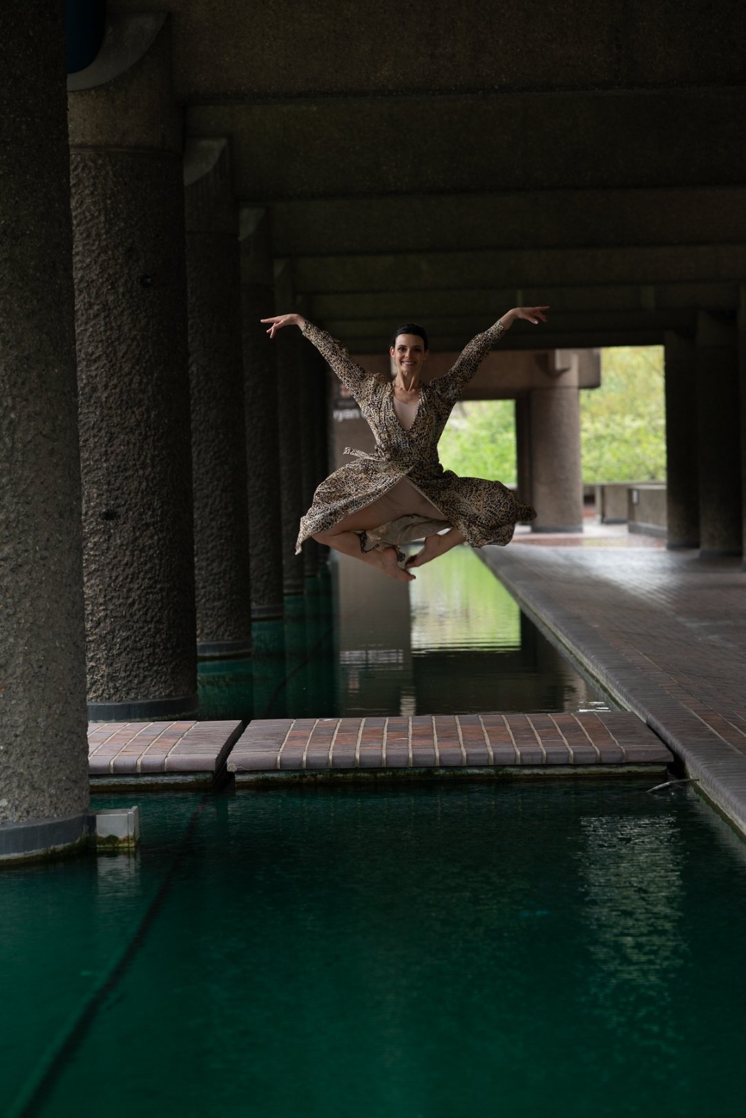 Sarah jumping over water at the Barbican in a leopard dress
