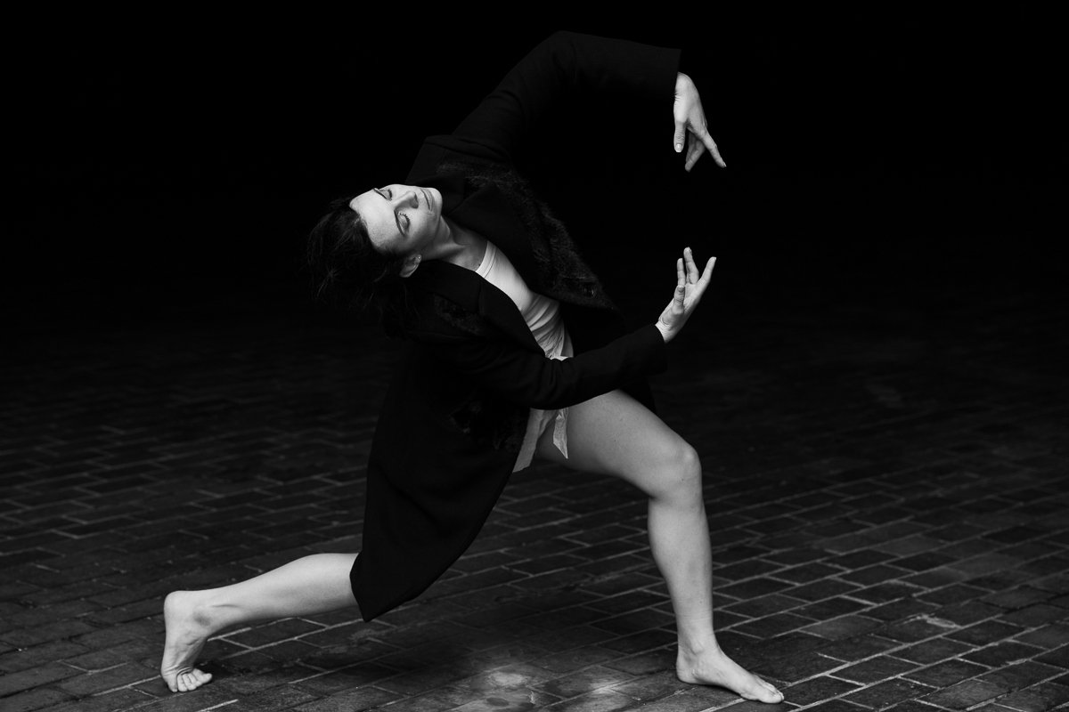 Sarah in a deep lunge with hands reaching, black and white